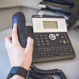 Hand hält Hörer vom Telefon
